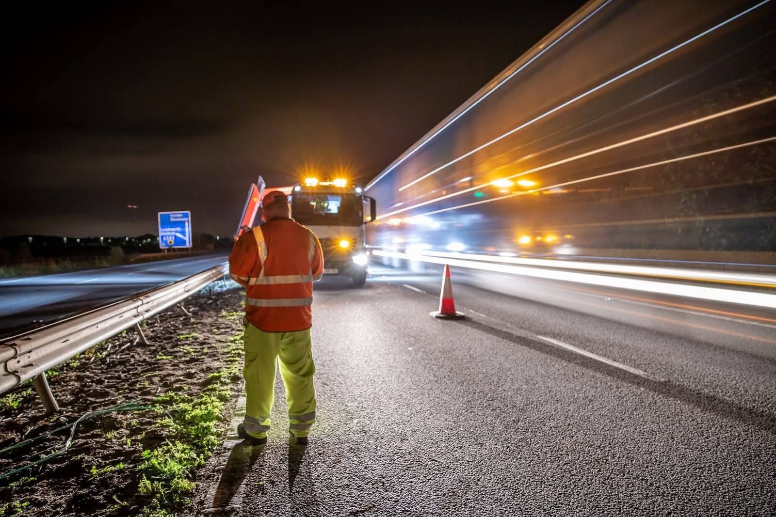 Recovery operator in high-visibility clothing at a motorway incident at night